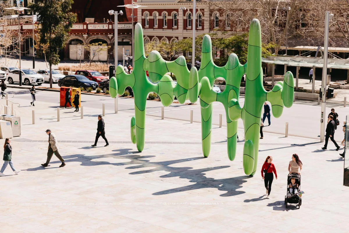 The green Cactus sculpture in Forrest Place, Perth, on a sunny day with people walking past